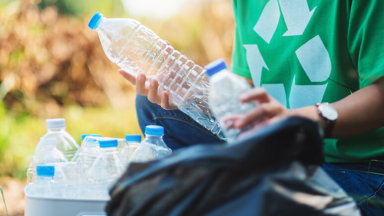 Person picking up plastic bottles for recycling image