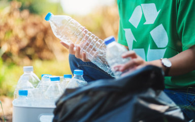 Person picking up plastic bottles for recycling image